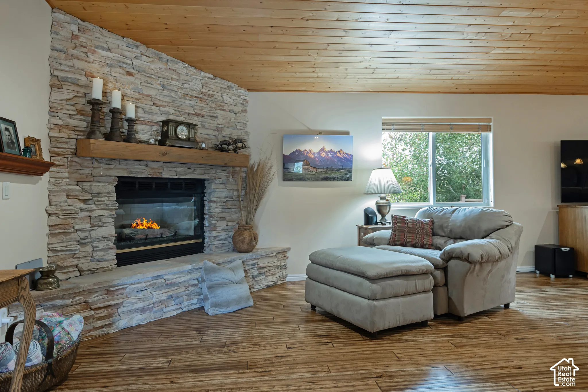 Stacked stone fireplace with a wood mantel, wood-finish flooring, and a wood plank ceiling