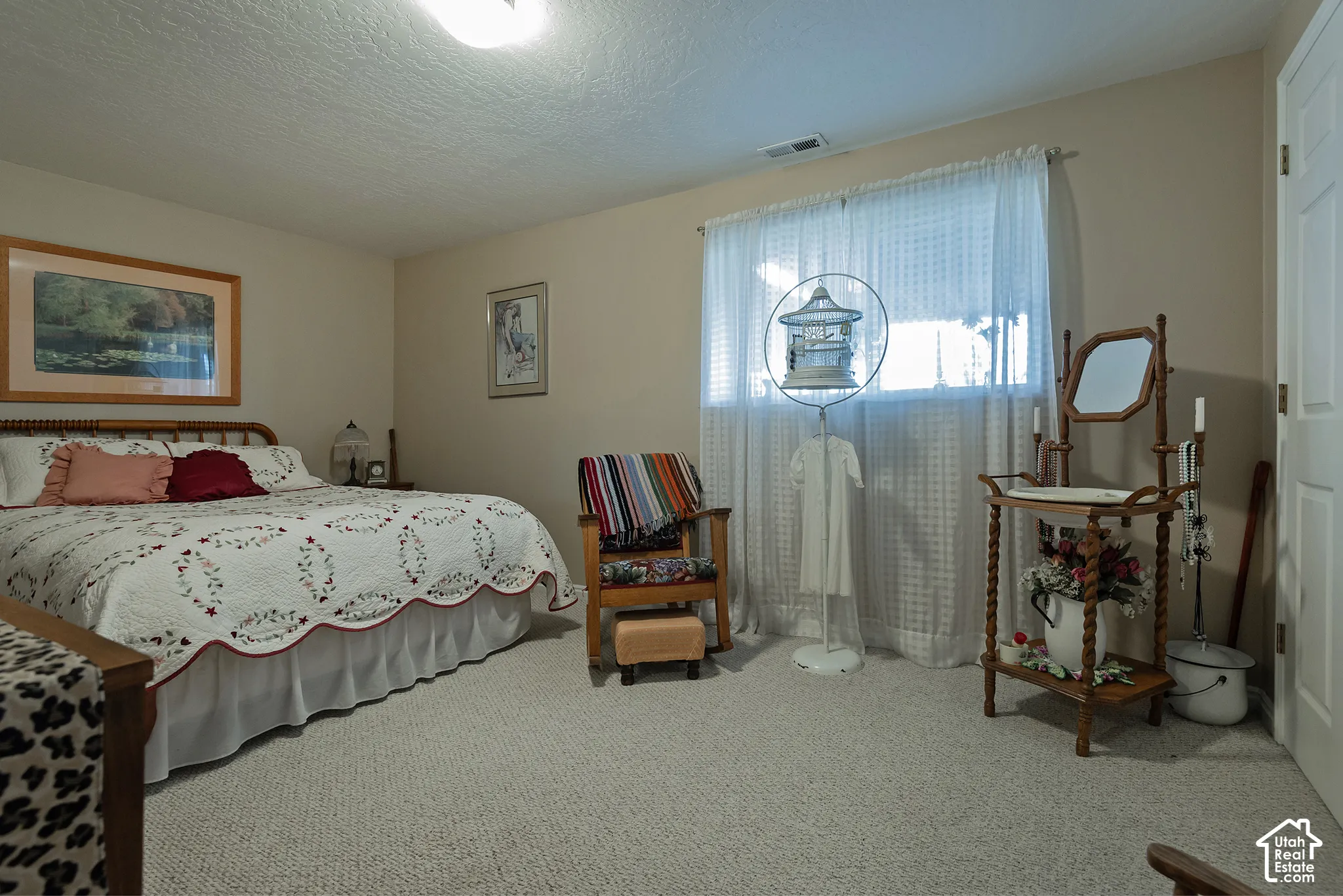 Light-colored carpet flooring, window with sheer curtains, neutral wall paint, white ceiling, and a white door with paneling