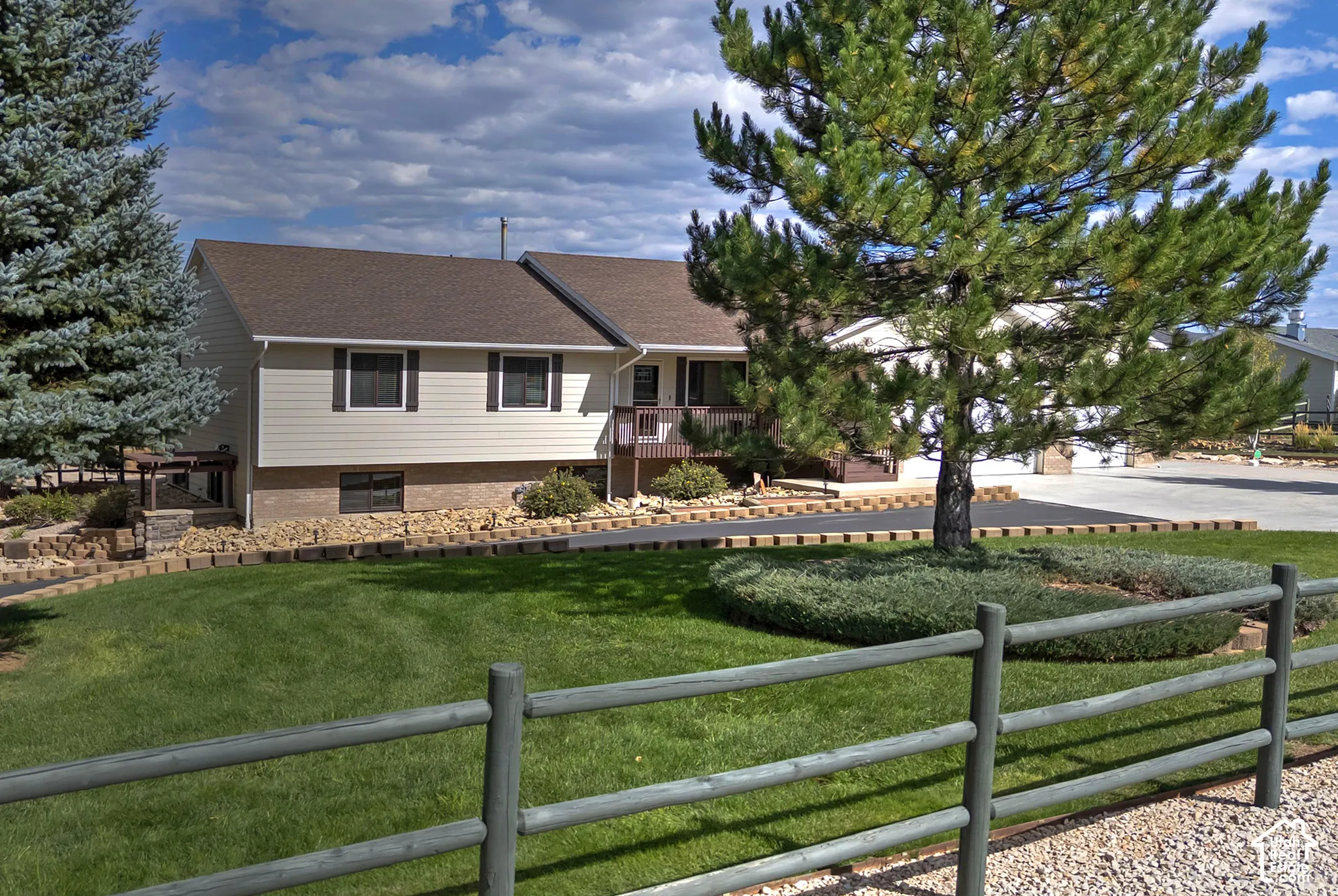 Split-level residence featuring light-colored siding and a brown shingle roof