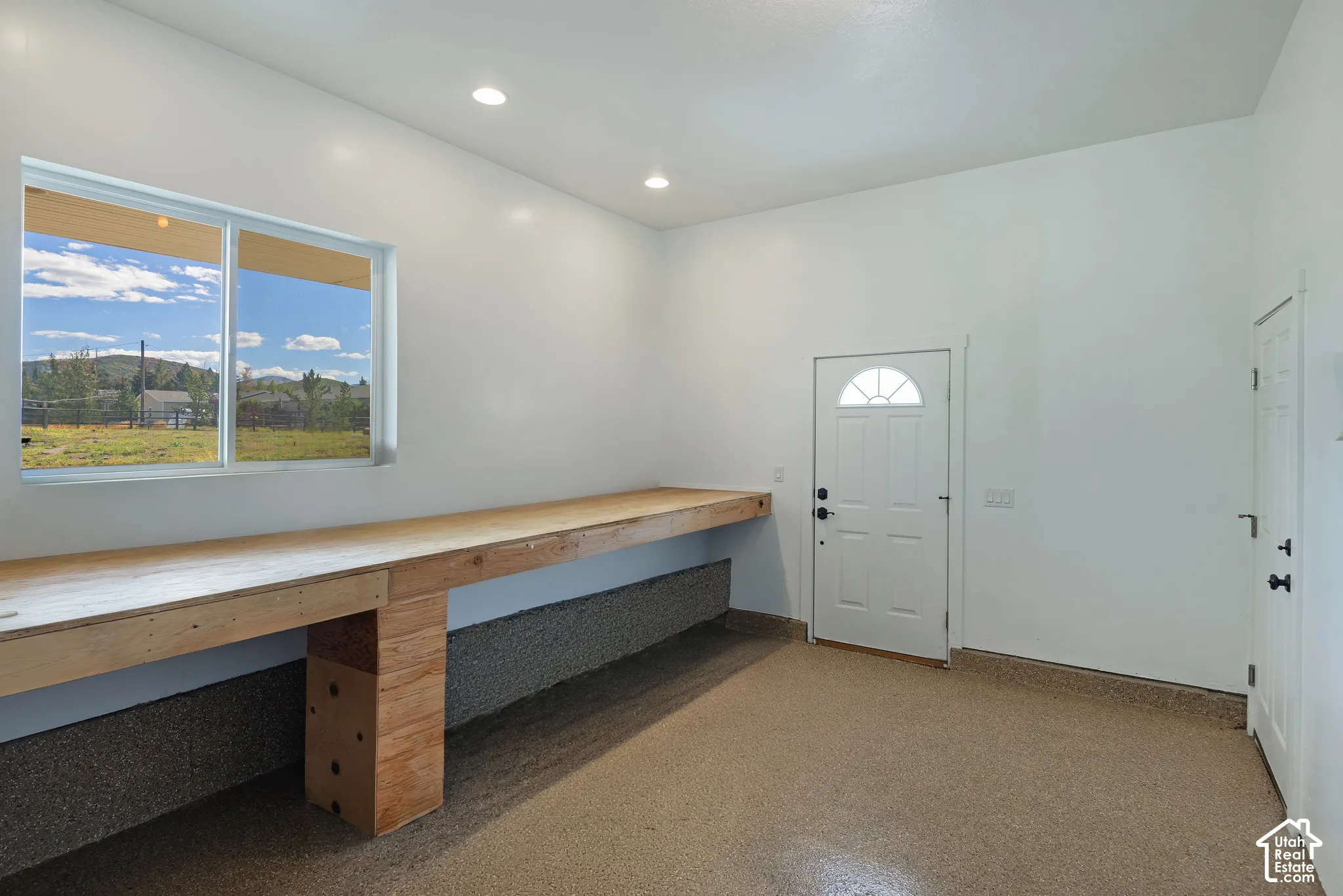 Expansive workshop area featuring a built-in workbench, large window, recessed lighting, and a durable epoxy-coated concrete floor