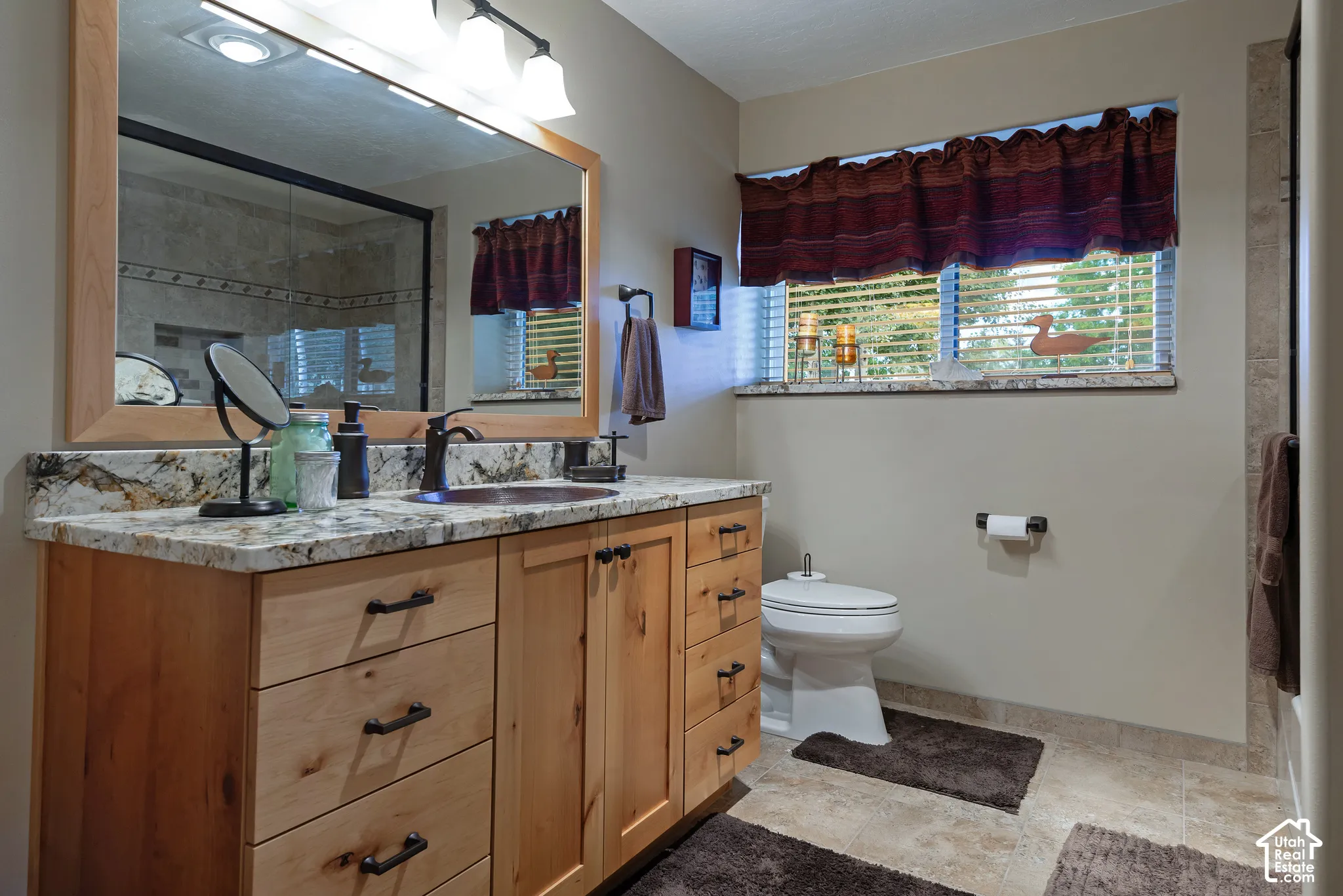 Wood-finish vanity with a granite countertop, undermount sink, and bronze-finish faucet