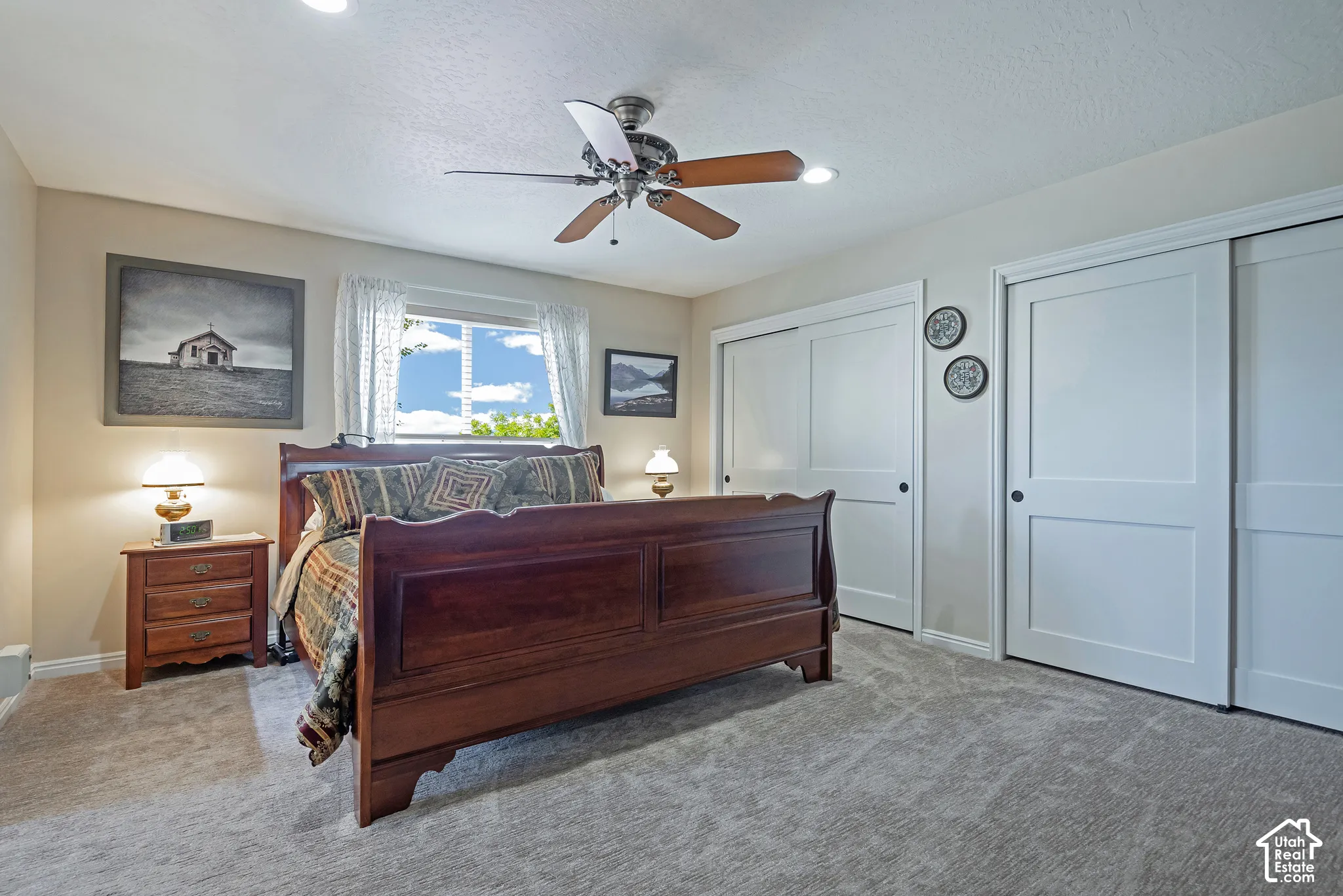 Recessed ceiling lighting, ceiling fan fixture, window with natural light, two sliding closet doors, and light-colored carpeting