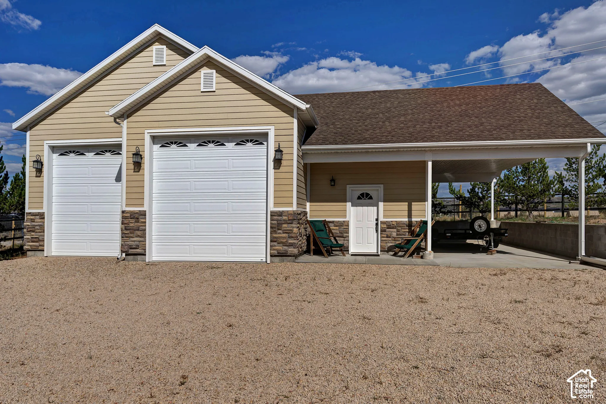 Attached two-car garage with overhead doors featuring arch window inserts, stone accents, and exterior wall lanterns