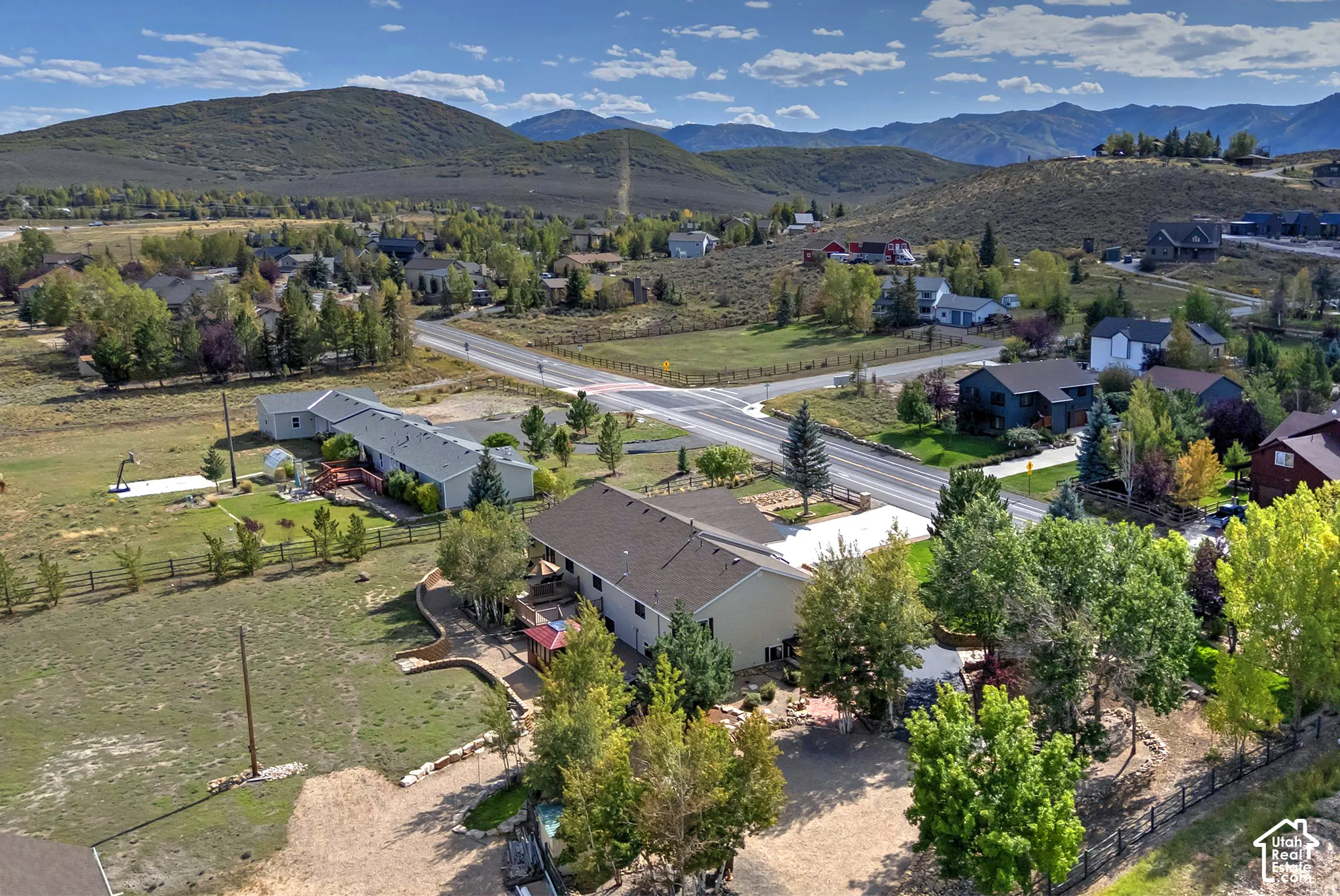 Expansive property featuring a large house with a multi-level deck, a separate structure, and surrounding mountainous terrain