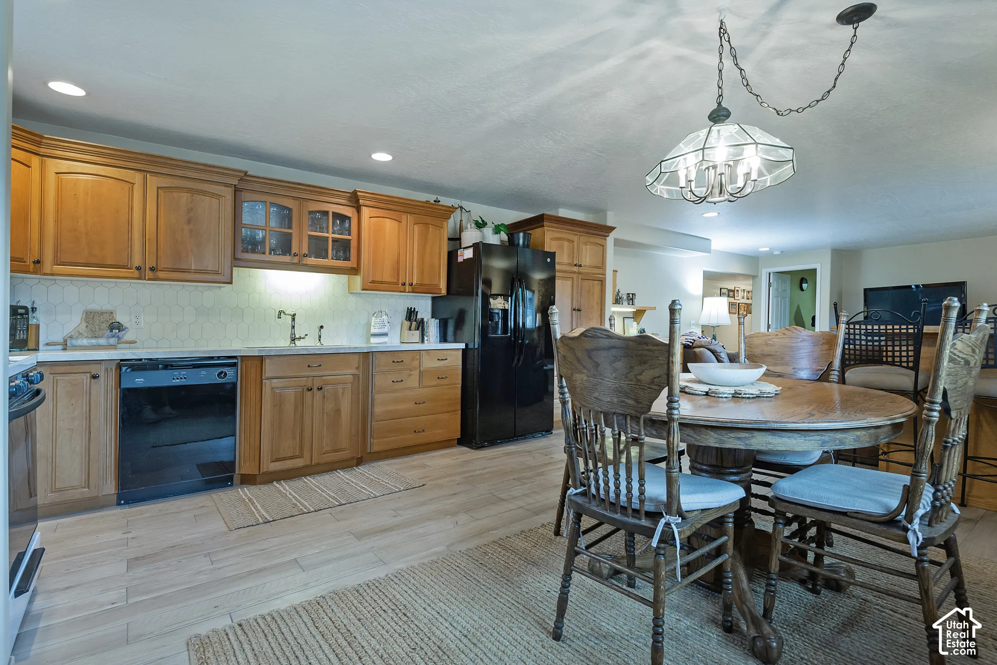 Kitchen featuring wood-finish cabinetry, light-toned countertops, and a full-size black dishwasher