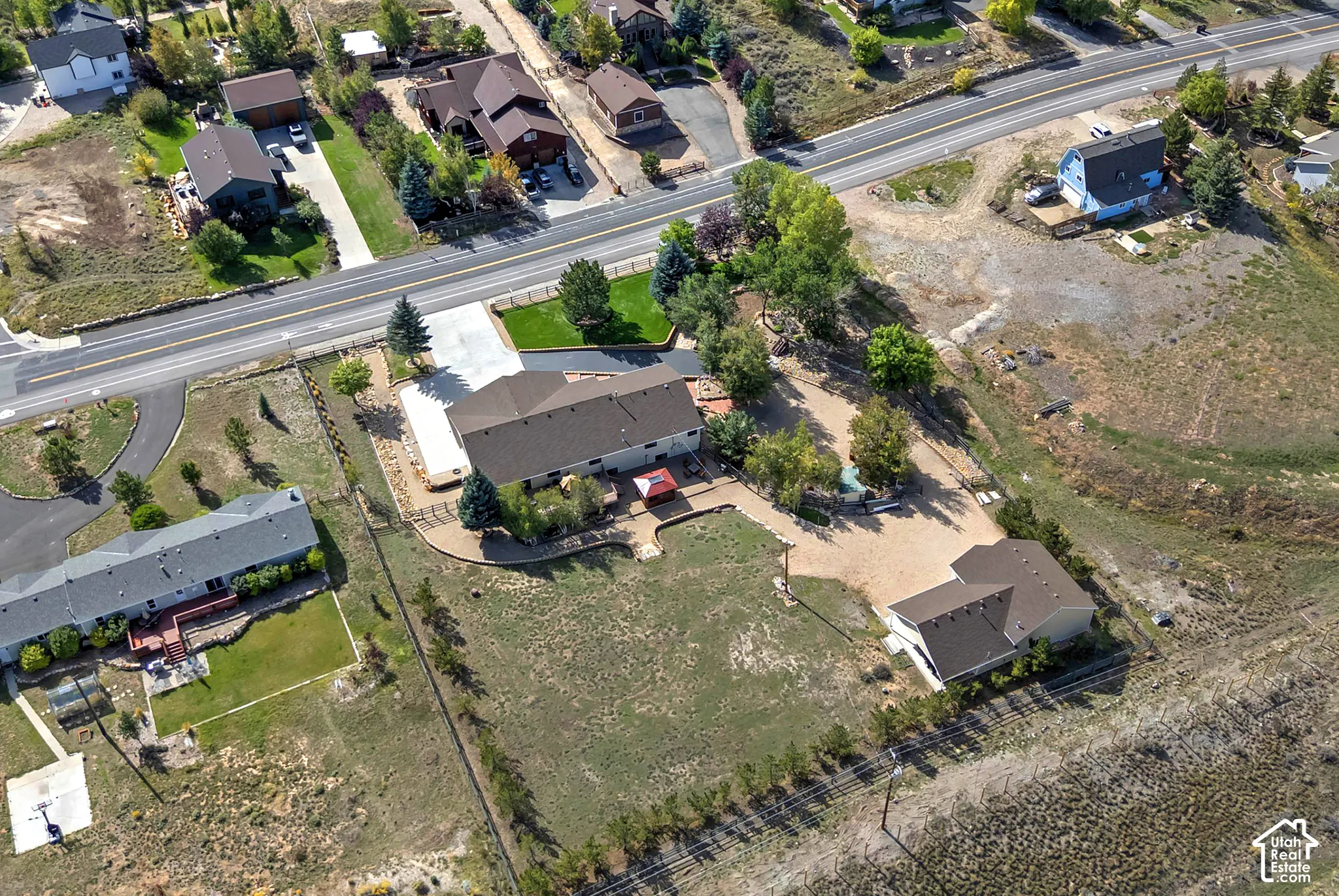 Expansive property featuring multiple structures, a paved driveway, and established landscaping