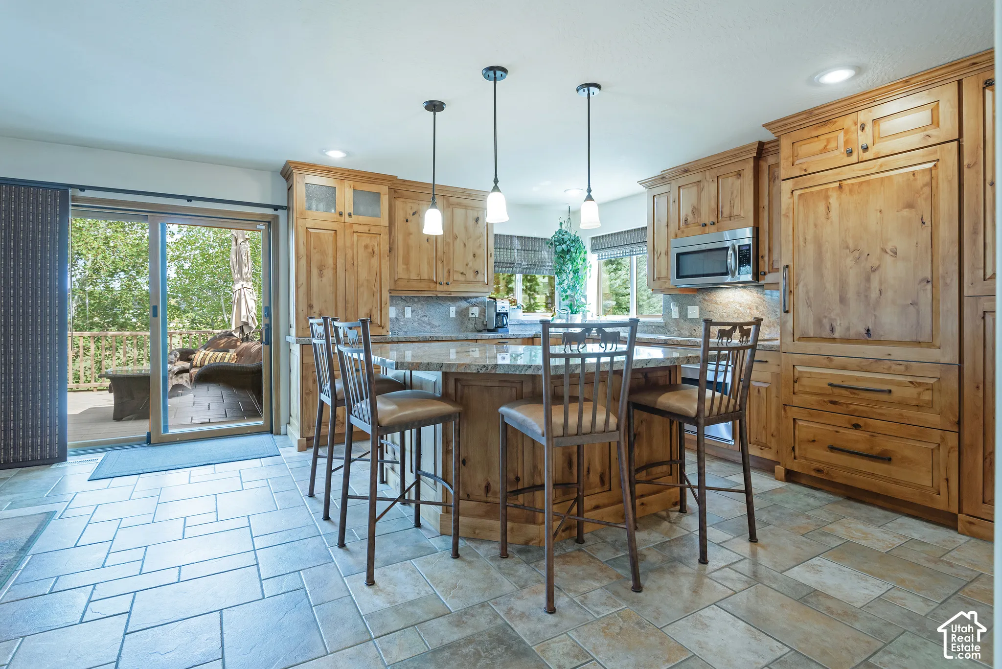 Kitchen featuring wood cabinetry, a center island with pendant lighting, a built-in microwave, and tile flooring