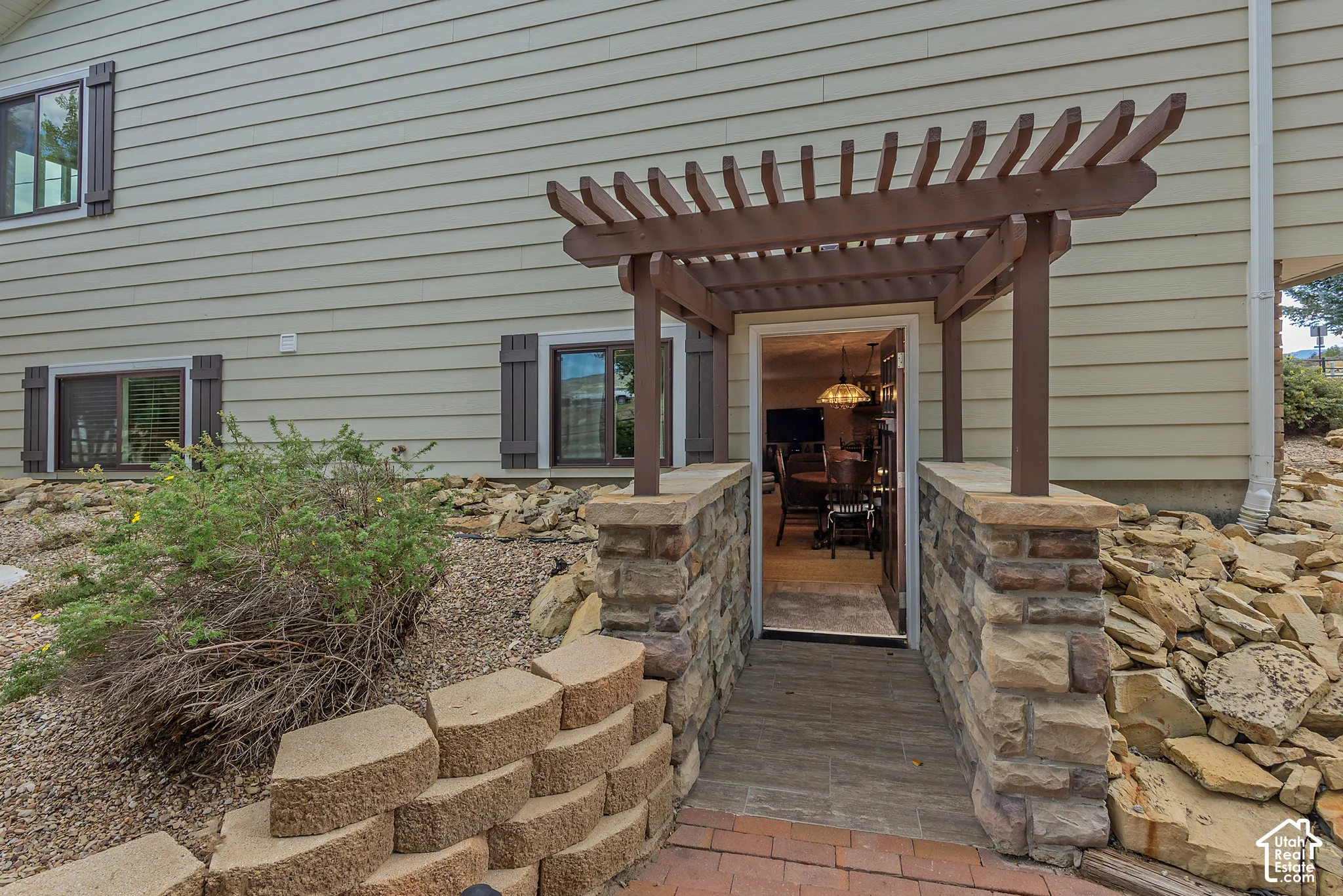 Entryway featuring a wood pergola and stone veneer columns