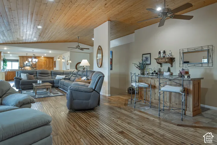 Vaulted wood-paneled ceiling, wood-finish flooring, recessed lighting, ceiling fan, and a built-in bar