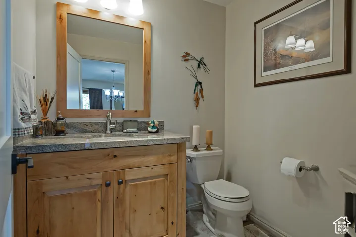 Wood-finish vanity with dual-door cabinetry, granite countertop, and undermount sink