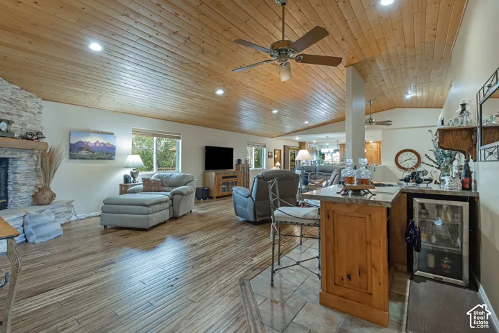 Wood-finish flooring with a stone fireplace, wood paneled ceiling, and ceiling fans