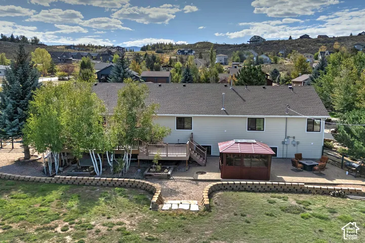 Expansive backyard featuring a large deck, screened gazebo, and a paved patio area