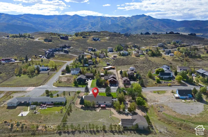 Expansive property featuring a dwelling with a multi-level deck, surrounding natural terrain, and distant mountain scenery