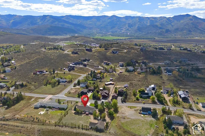 Mountain backdrop, scattered residential homes, paved roads, established trees, and open terrain