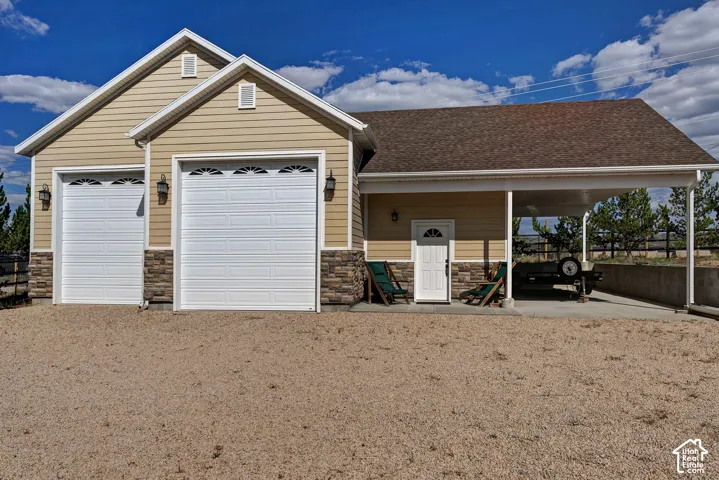 Attached two-car garage with overhead doors featuring arch window inserts, stone accents, and exterior wall lanterns