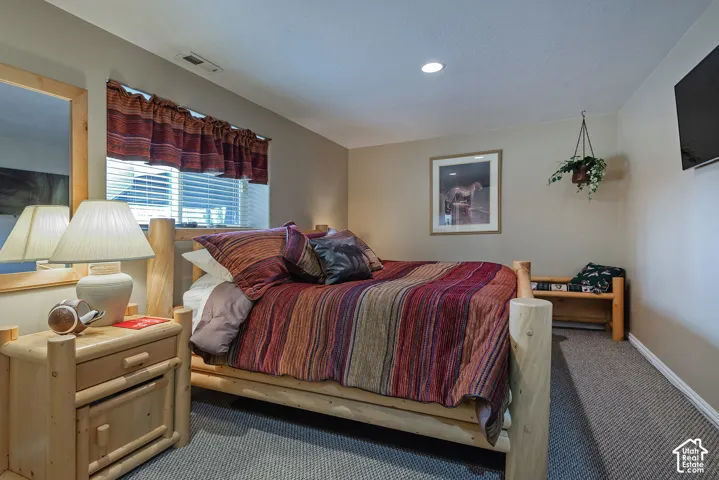 Recessed ceiling lighting, wall-mounted television, and a window with blinds