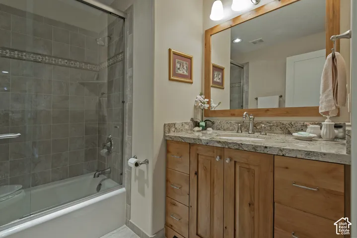 Wood-finish vanity with a stone countertop, undermount sink, and polished chrome faucet