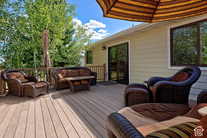Expansive wood-finish deck with a wood railing, siding exterior, and sliding glass door