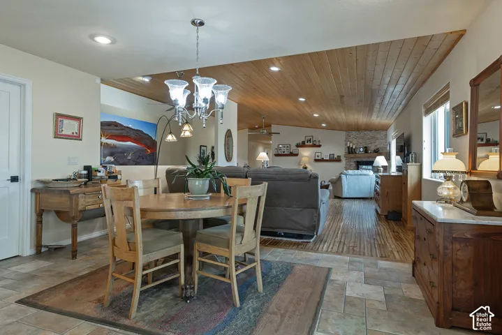 Tile flooring in dining area, wood-finish flooring in living area, wood-plank ceiling, recessed lighting, and stone fireplace surround