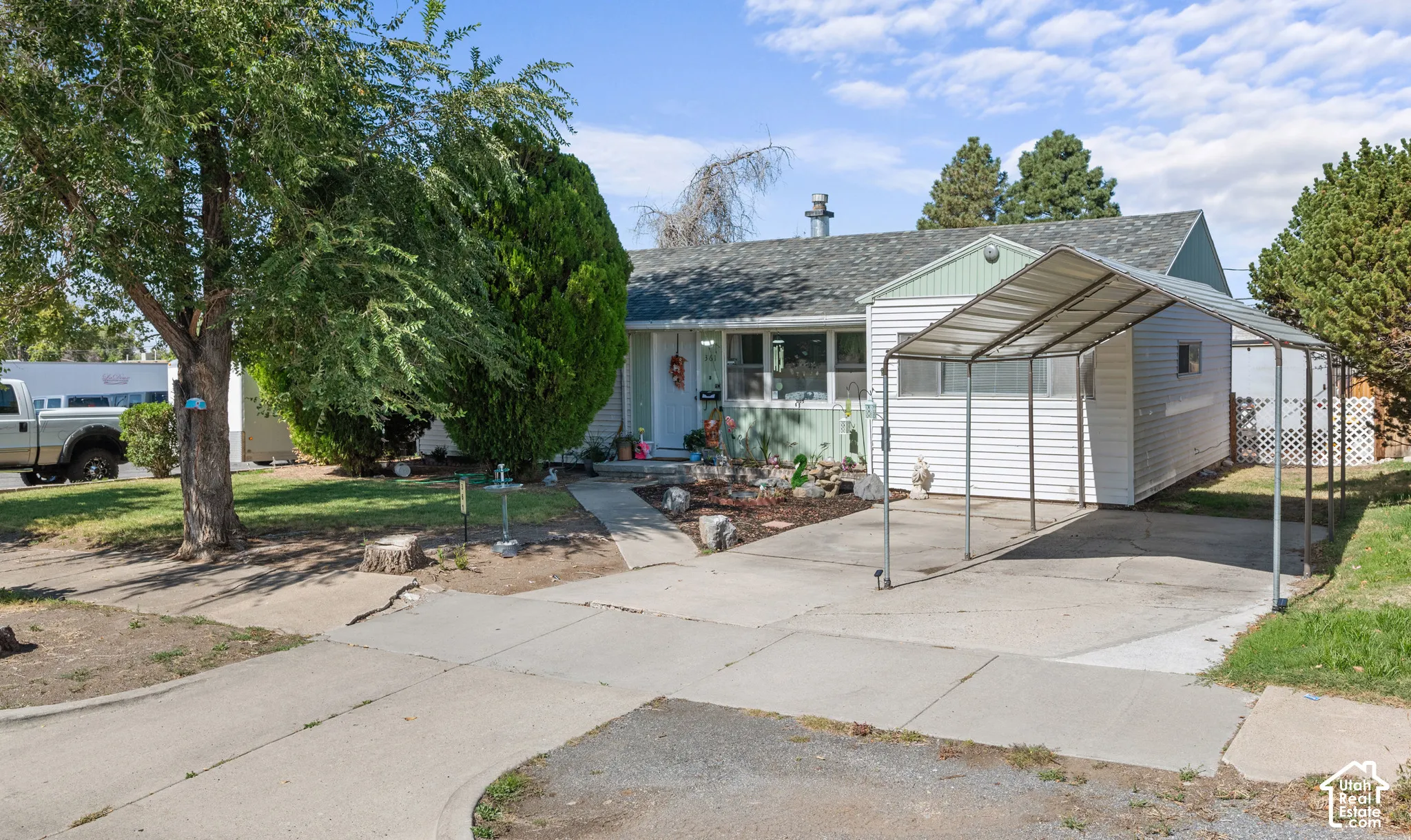Ranch-style residence featuring a carport, concrete driveway, and established front landscaping