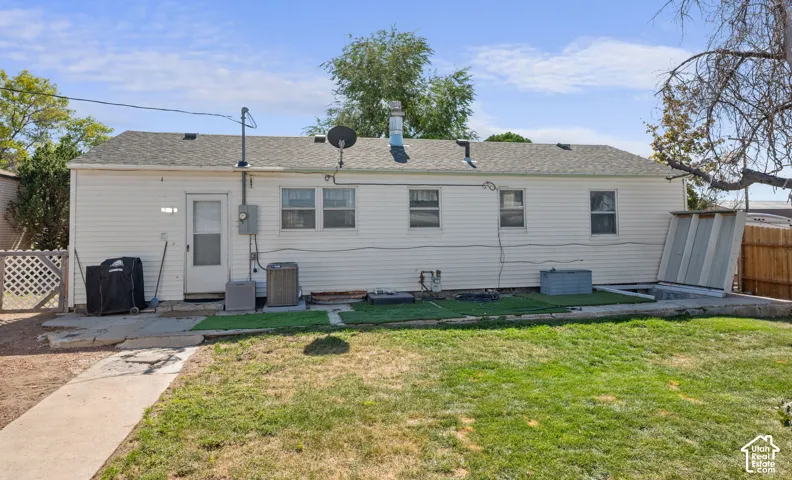 White siding exterior with multiple windows, a rear entry door, and a partially grassed yard