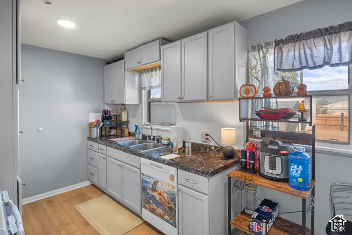 Recessed ceiling lighting, wood-finish flooring, white cabinetry with silver-tone hardware, dark speckled countertop, and a double basin stainless steel sink