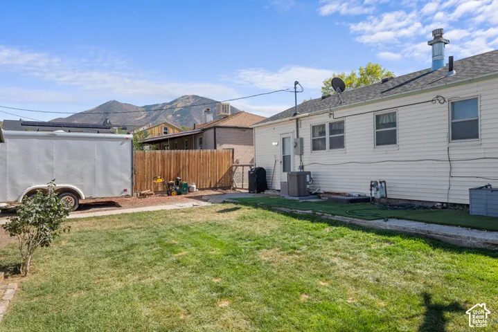 Expansive backyard with a manicured lawn, a full wood privacy fence, and a paved area
