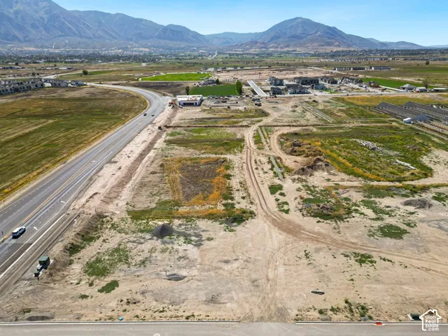 Expansive undeveloped land featuring a paved road, mountainous backdrop, and distant structures