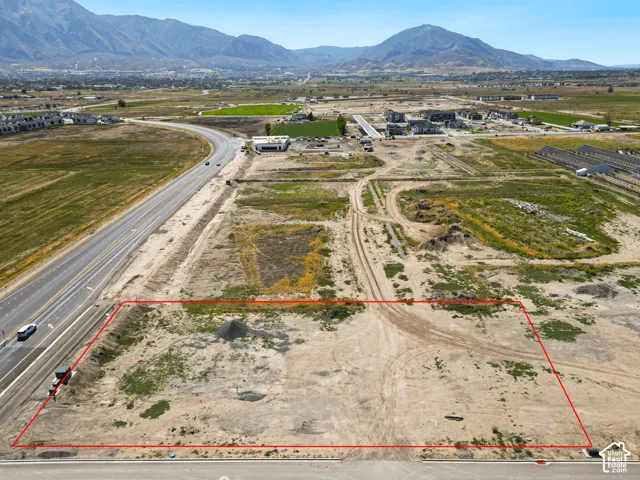 Expansive vacant land parcel featuring clear demarcation, direct road frontage, and distant mountain backdrops