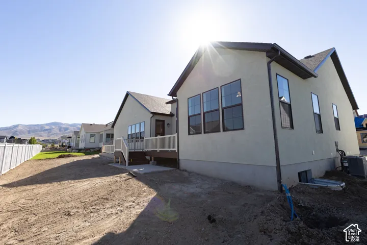 Stucco exterior with multiple windows, a rear deck with white railings, and a concrete patio