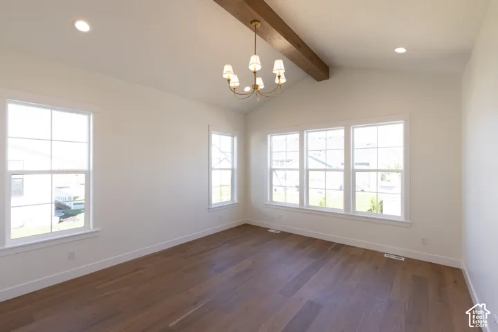 Vaulted ceiling with exposed wood-finish beam, recessed lighting, and a central chandelier