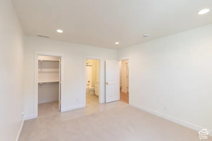 Recessed ceiling lighting, light-colored carpeting, white interior doors, and a built-in closet with shelving