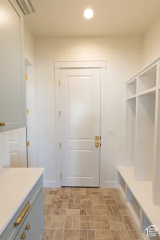 Recessed lighting, light-colored walls, tile flooring, built-in shelving, and light-toned cabinetry with gold-finish hardware
