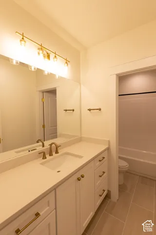 Vanity with single basin, solid surface countertop, white cabinetry, and brass-tone hardware