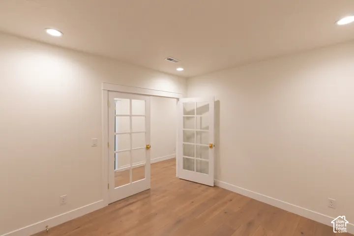 Recessed lighting, wood-finish flooring, white walls, and French doors with glass panes