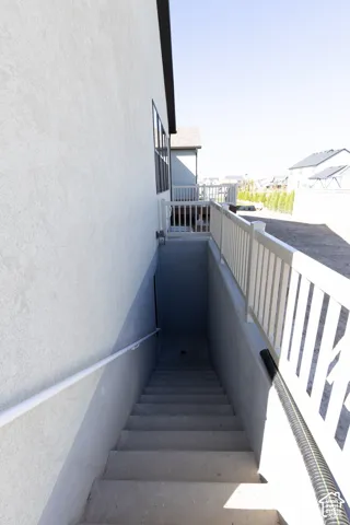 Exterior stucco finish, basement access, concrete staircase, white railing, and exterior window