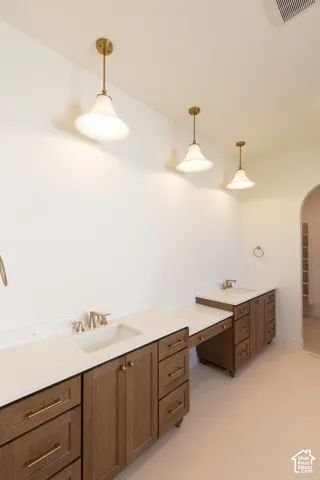 Dual wood-finish vanities with integrated sinks, light-toned countertops, and brass hardware