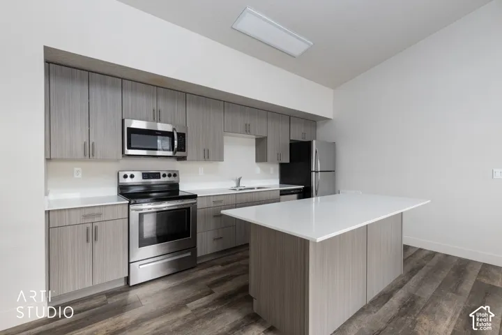 Contemporary kitchen featuring stainless steel appliances, wood-finish flooring, white countertops, and gray cabinetry