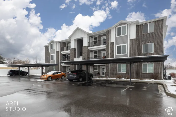 Multi-story building with brick and siding exterior, private balconies, and covered parking structures