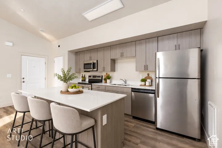 Kitchen featuring stainless steel appliances, wood-finish flooring, recessed lighting, and a kitchen island with a light-colored countertop