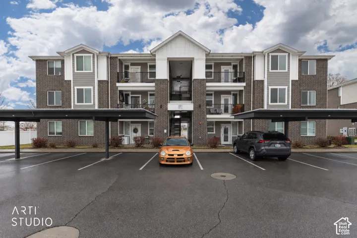Exterior featuring brick and siding facade, multiple balconies with black railings, and covered parking structures