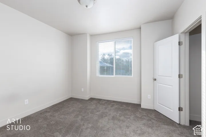 Wall-to-wall carpeting with a neutral finish, white walls, and a window with horizontal blinds