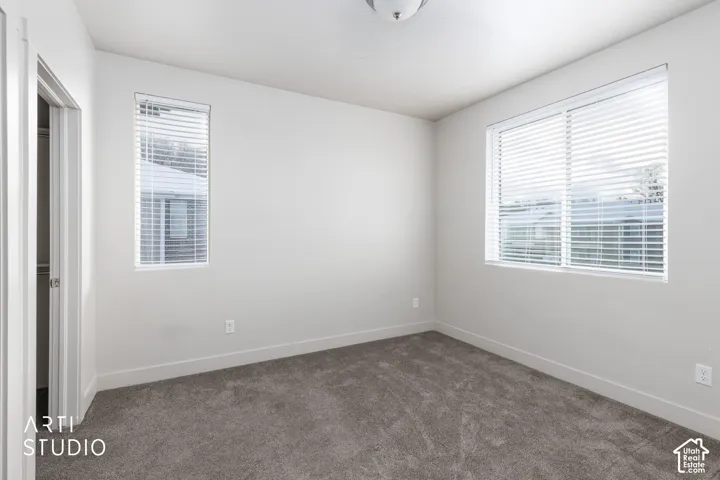 Plush carpet flooring, neutral paint palette, multiple windows with blinds, and a flush mount ceiling light