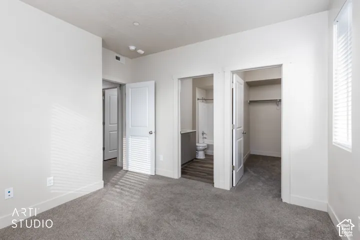 Plush gray carpeting, white painted walls, a built-in closet with shelving and hanging rod, and white window blinds
