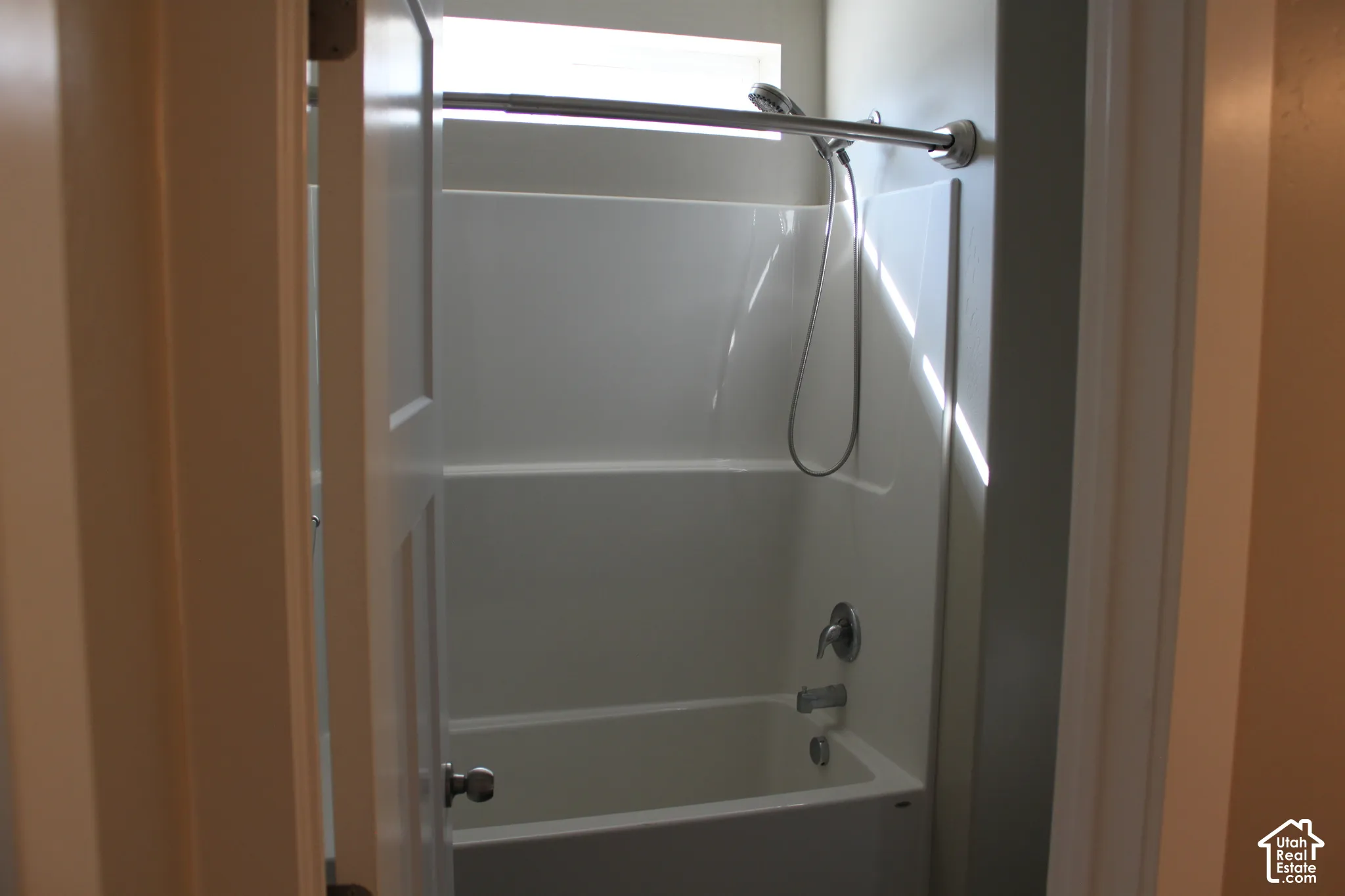 Bathtub with shower combination featuring a curved shower rod and silver-toned fixtures on suite to the primary bedroom