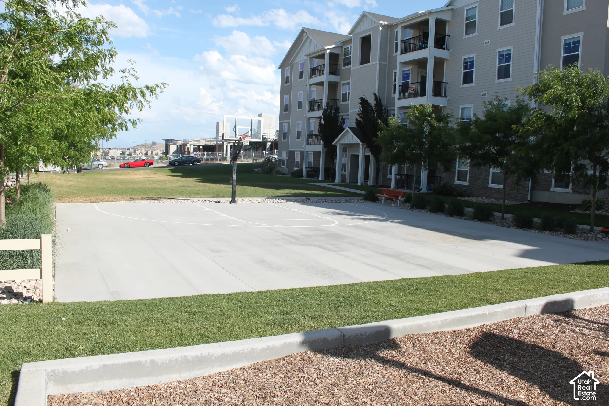 Outdoor basketball court with a paved surface and perimeter landscaping