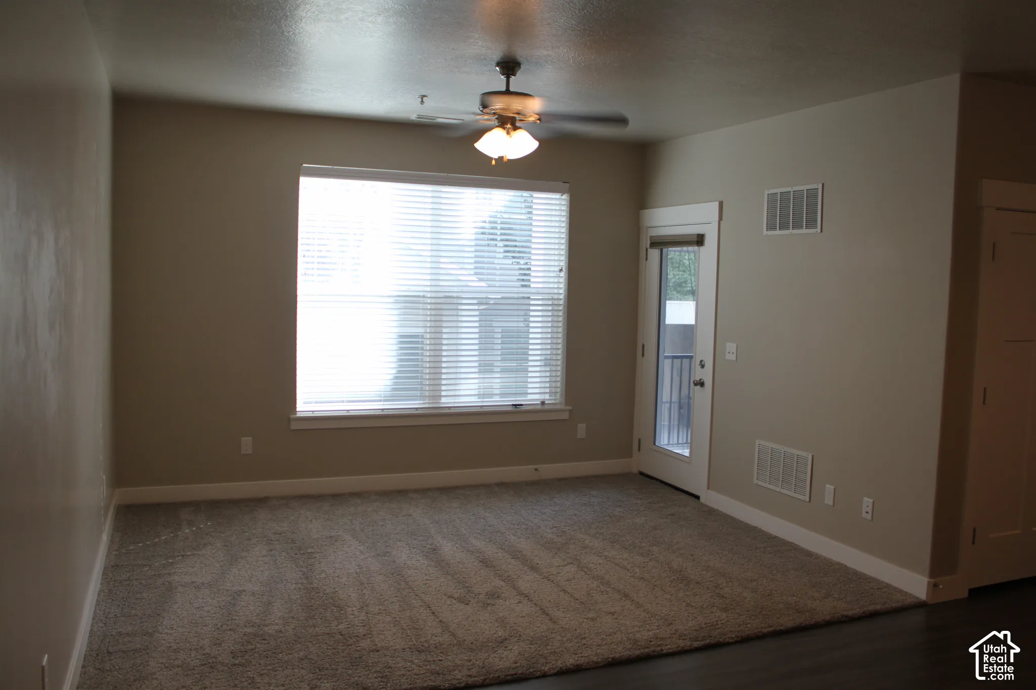 Neutral-toned walls, ceiling fan with integrated lighting, large window with blinds, and white trim throughout with door to covered porch