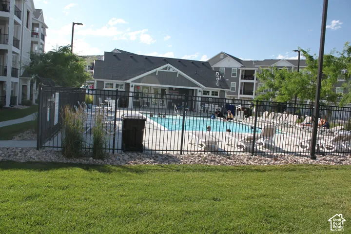 Outdoor swimming pool with a surrounding fence, concrete deck, and ample lounge seating