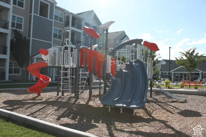 Playground with multiple slides and climbing structures on a wood chip surface, bordered by a concrete curb