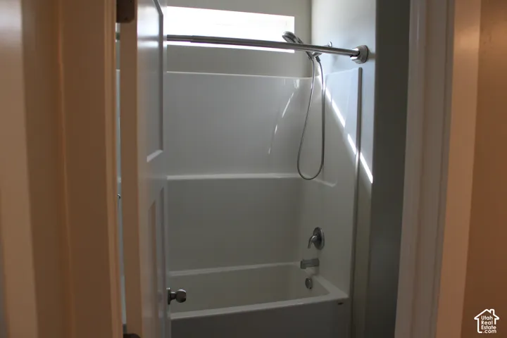 Bathtub with shower combination featuring a curved shower rod and silver-toned fixtures on suite to the primary bedroom